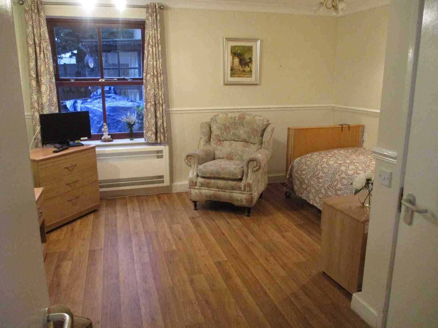 one of our bedrooms with a bed, armchair and tv in the corner